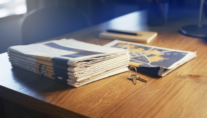 Firefly realistic photograph of a stack of folded newspapers on a wooden desk beside a printe 173156